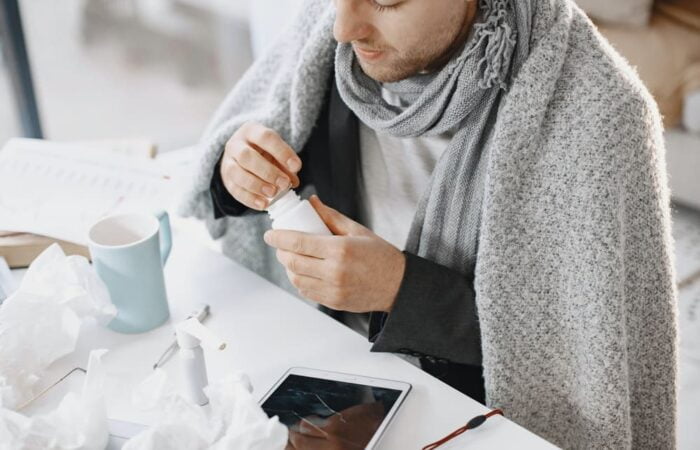 pessoa com um xale e cachecol com um frasco de remédios na mão