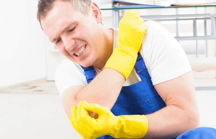 homem de luvas amarelas e macação azul se contundindo no trabalho