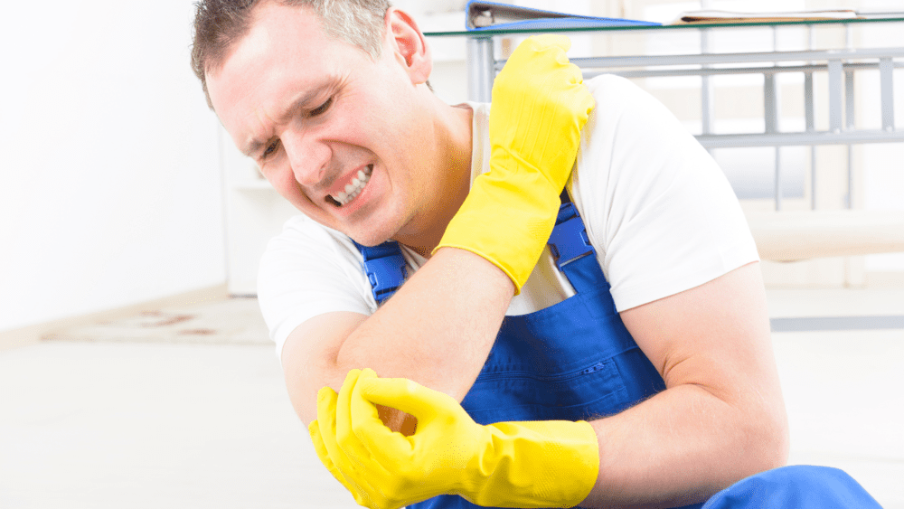 homem de luvas amarelas e macação azul se contundindo no trabalho