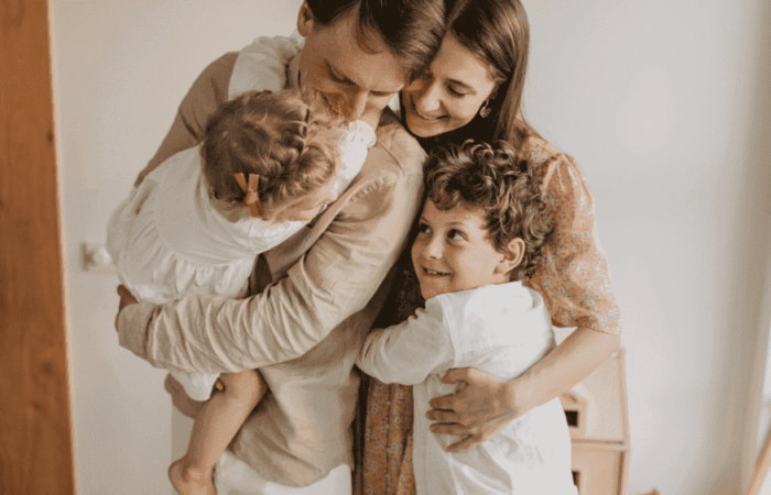 família de pai, mão e um casal de filhos abraçados e sorrindo