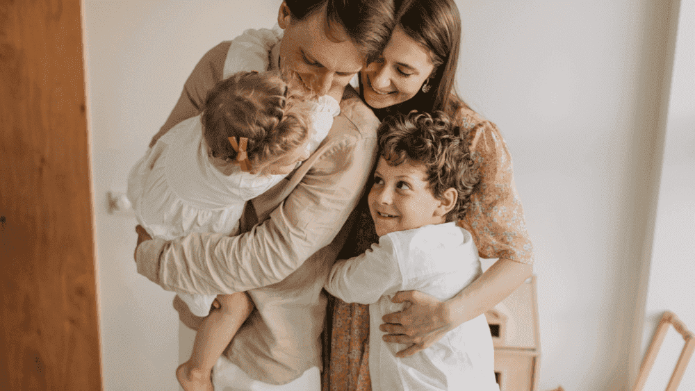 família de pai, mão e um casal de filhos abraçados e sorrindo