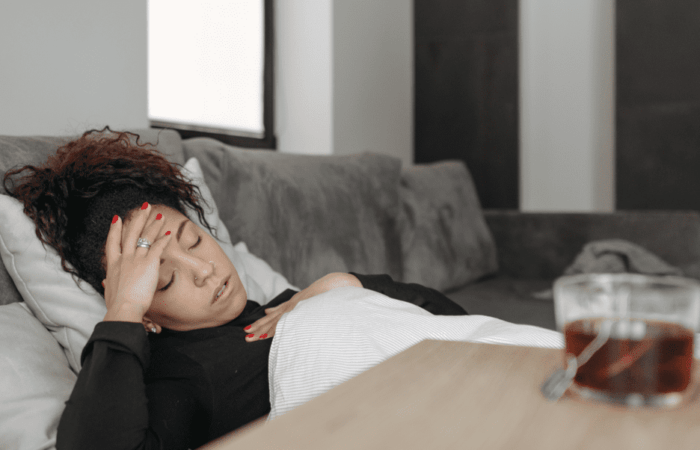 pessoa deitada com a mão na cabeça passando mal