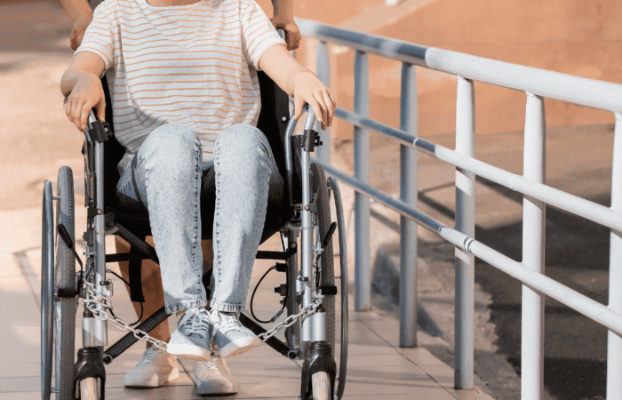pessoa empurrando a cadeira de rodas de uma pessoa com deficiência